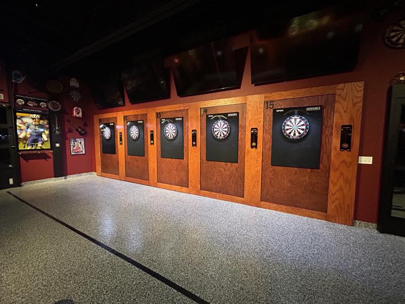 Five numbered dartboard bays, 11 through 15, along a red wall.
