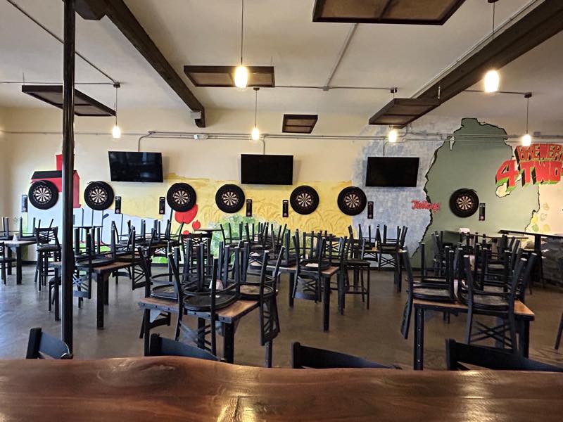 The dart wall at Brewery 4 two 4, with boards mounted along a painted mural of a Michigan landscape.