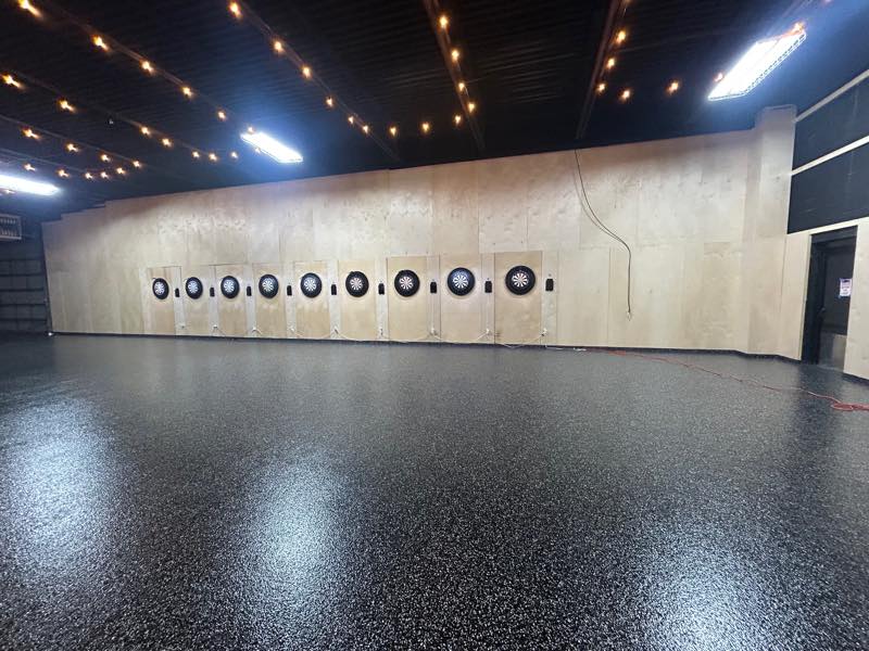 Nine dartboards spaced along the plywood wall of the tournament room.
