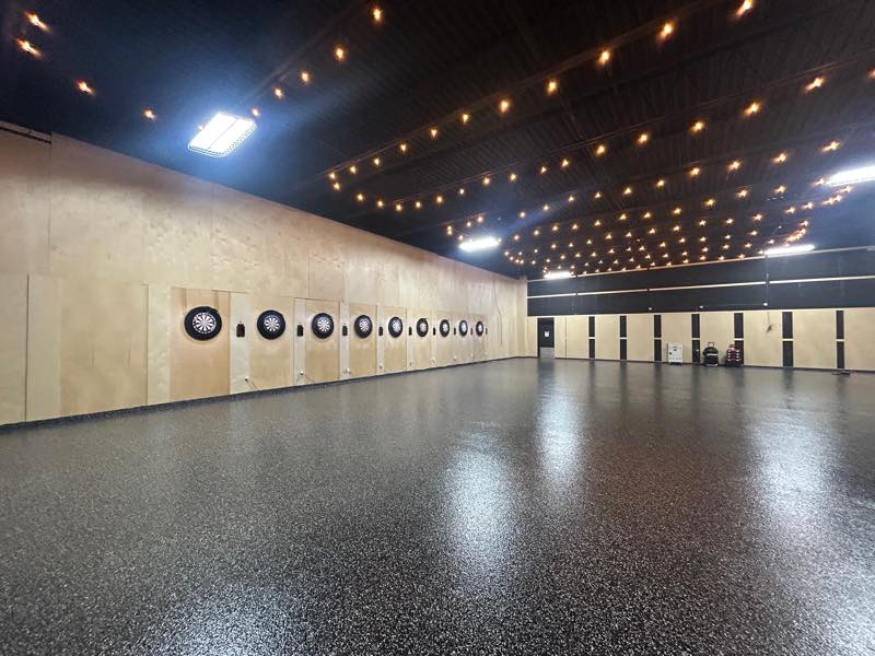 The tournament room looking down its length, boards on the left and string lights overhead.